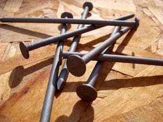 Nägel auf Holzstück aufgestapelt